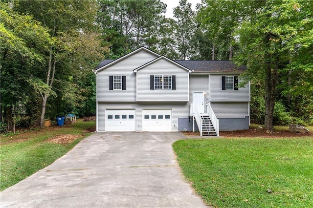 raised ranch featuring a front yard, driveway, and an attached garage