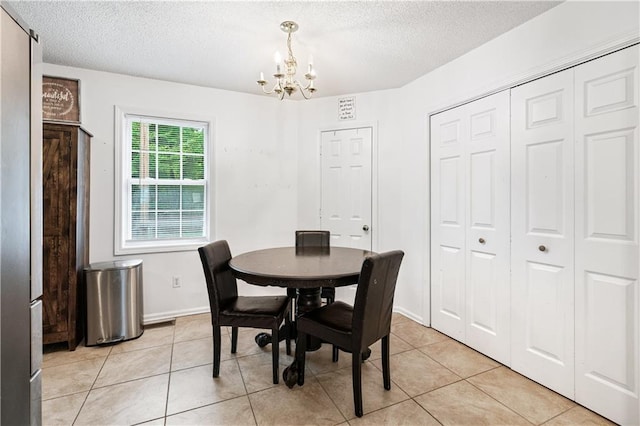 dining room featuring light tile patterned floors, baseboards, a chandelier, and a textured ceiling