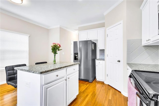 kitchen featuring stainless steel fridge, a kitchen island, white cabinetry, and tasteful backsplash