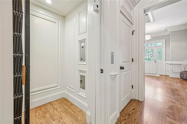 corridor with crown molding, elevator, and light wood-type flooring