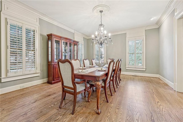 dining area with an inviting chandelier, ornamental molding, and light wood-type flooring