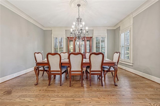 dining area with hardwood / wood-style floors, crown molding, and a chandelier