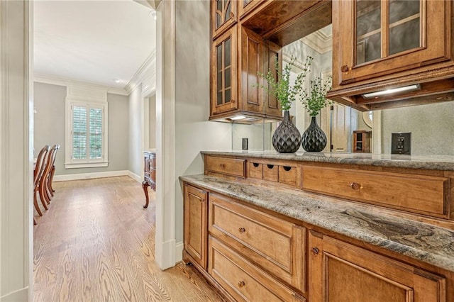 kitchen featuring ornamental molding, light stone counters, and light wood-type flooring