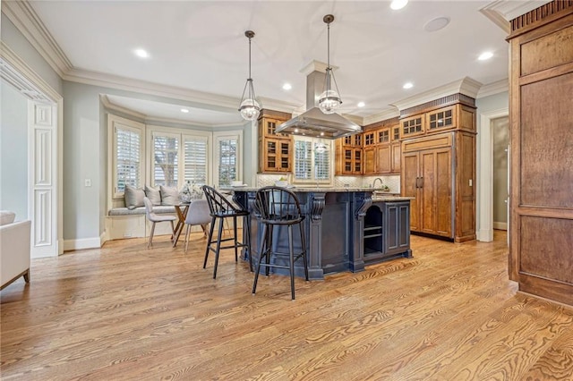 kitchen featuring ornamental molding, light hardwood / wood-style flooring, pendant lighting, and a breakfast bar area