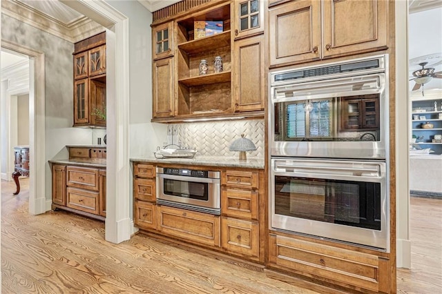 kitchen featuring light stone countertops, backsplash, double oven, crown molding, and light hardwood / wood-style flooring