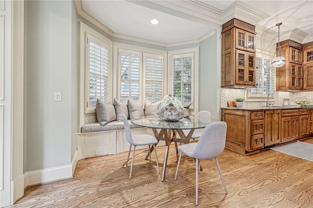 dining room with ornamental molding, sink, breakfast area, and light wood-type flooring