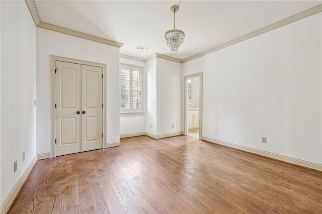 unfurnished bedroom featuring an inviting chandelier, hardwood / wood-style flooring, and crown molding