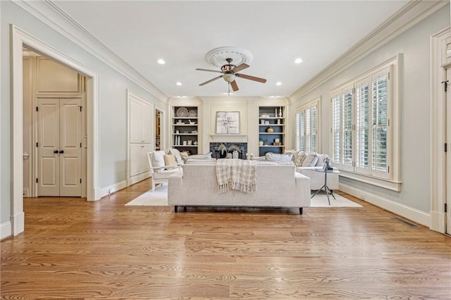 living room with crown molding, built in features, light hardwood / wood-style floors, and ceiling fan