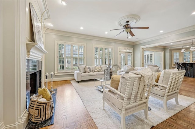 living room featuring ornamental molding, light wood-type flooring, and ceiling fan