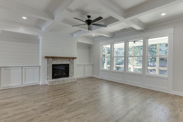 unfurnished living room featuring beamed ceiling, a fireplace, coffered ceiling, and light hardwood / wood-style flooring