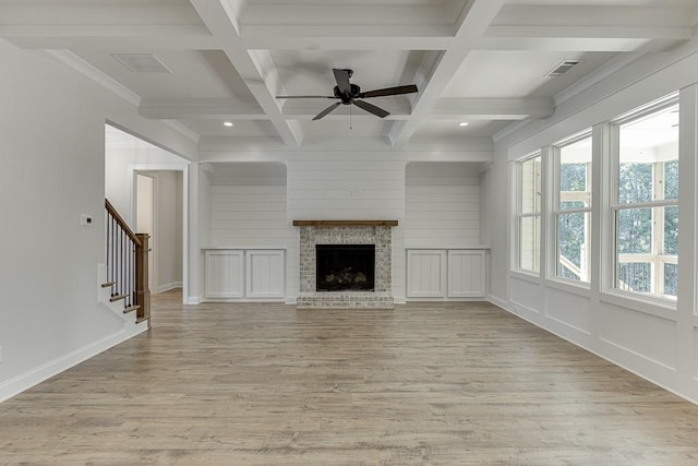 unfurnished living room featuring beamed ceiling, coffered ceiling, a fireplace, and light hardwood / wood-style floors