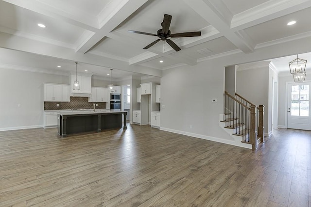 unfurnished living room with beamed ceiling, wood-type flooring, coffered ceiling, and sink