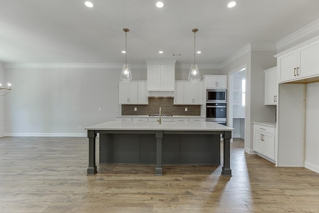 kitchen with a kitchen island with sink, sink, decorative light fixtures, and appliances with stainless steel finishes