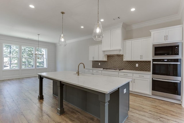 kitchen with a kitchen island with sink, sink, stainless steel appliances, and white cabinets