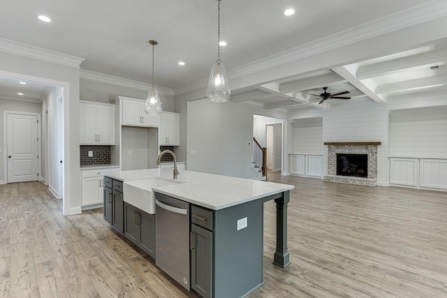 kitchen featuring sink, white cabinetry, hanging light fixtures, an island with sink, and stainless steel dishwasher