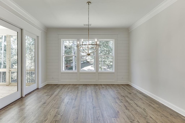 unfurnished dining area with crown molding, light hardwood / wood-style floors, and a chandelier