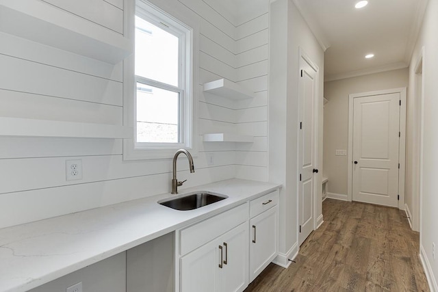 kitchen with sink, crown molding, dark hardwood / wood-style floors, light stone countertops, and white cabinets