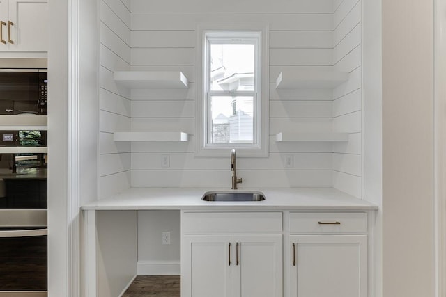 bar with white cabinetry, wood-type flooring, and sink