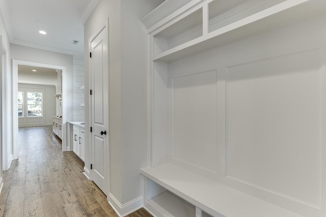 mudroom with crown molding and hardwood / wood-style floors