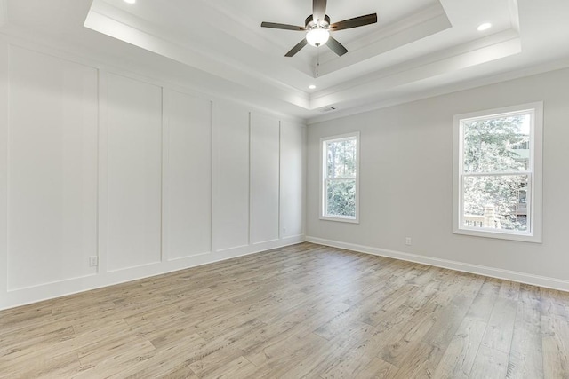 unfurnished room with ornamental molding, a raised ceiling, ceiling fan, and light wood-type flooring