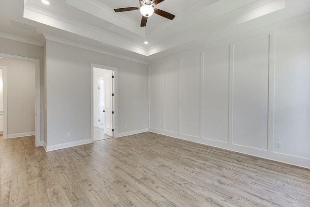 unfurnished room featuring ceiling fan, ornamental molding, a raised ceiling, and light hardwood / wood-style floors