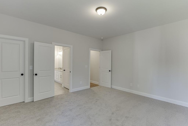 unfurnished bedroom with light colored carpet and connected bathroom