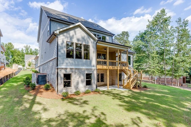 rear view of property with a wooden deck, a yard, and ceiling fan