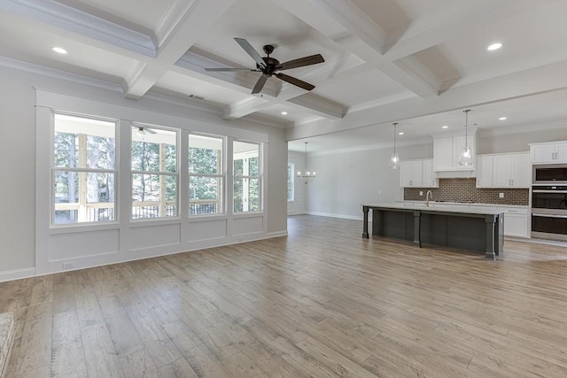 unfurnished living room with beam ceiling, plenty of natural light, coffered ceiling, and light hardwood / wood-style floors