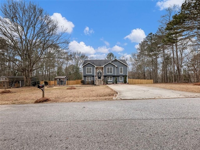 bi-level home with concrete driveway and fence