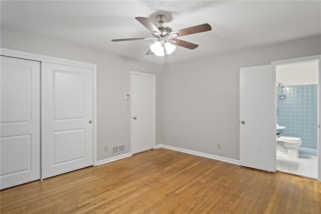 unfurnished bedroom with light wood finished floors, a closet, visible vents, ensuite bathroom, and baseboards