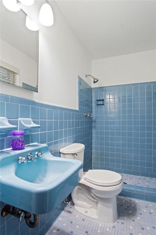 bathroom featuring tile walls, toilet, a stall shower, wainscoting, and tile patterned flooring