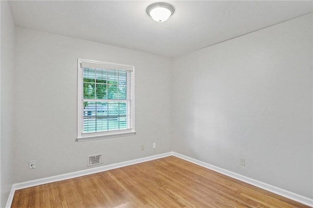 empty room featuring visible vents, baseboards, and wood finished floors