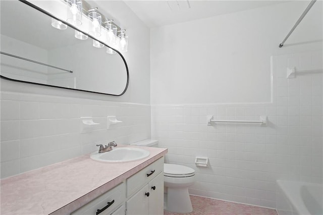 bathroom featuring toilet, wainscoting, vanity, and tile walls