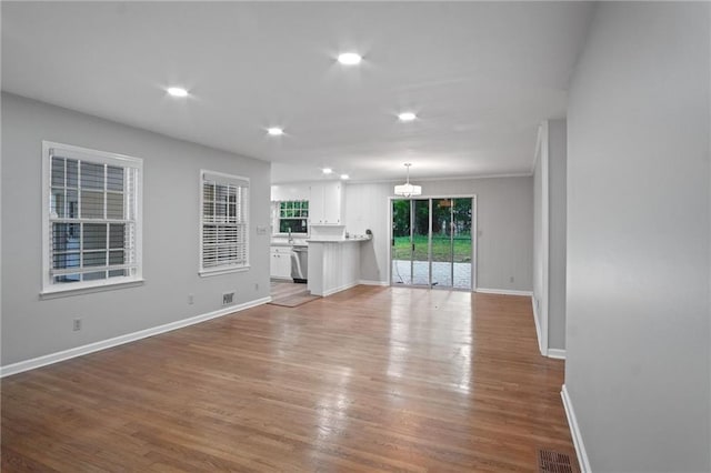 unfurnished living room featuring light wood finished floors, recessed lighting, visible vents, ornamental molding, and baseboards