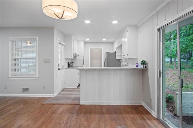 kitchen featuring a peninsula, dark wood-style floors, white cabinetry, and freestanding refrigerator