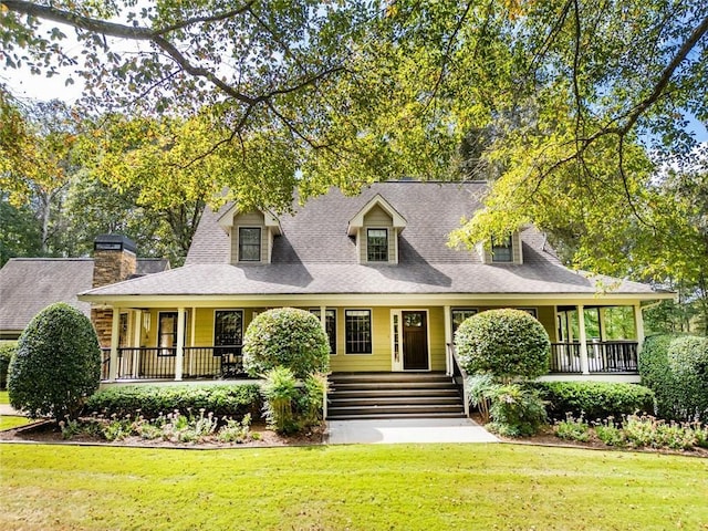 view of front of home with covered porch, a front lawn, and a shingled roof