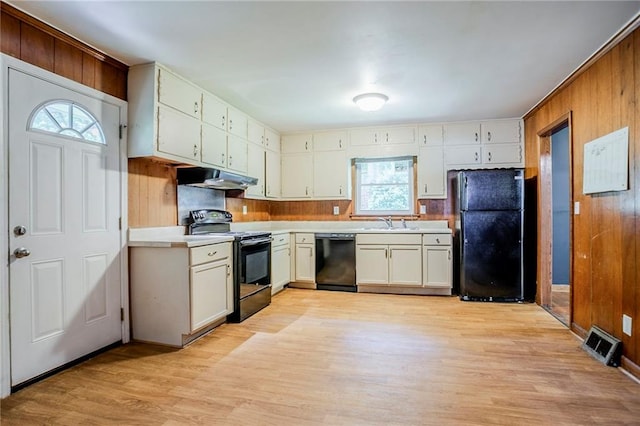 2201 Bollingbrook Dr, Atlanta, GA 30311 - kitchen with black appliances, under cabinet range hood, light countertops, light wood finished floors, and wood walls