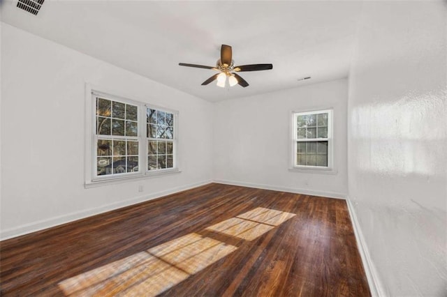 empty room with wood finished floors, baseboards, visible vents, and ceiling fan