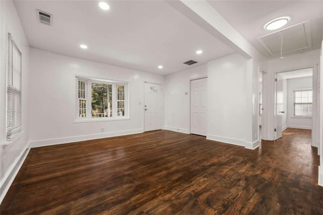 empty room with attic access, wood finished floors, visible vents, and baseboards