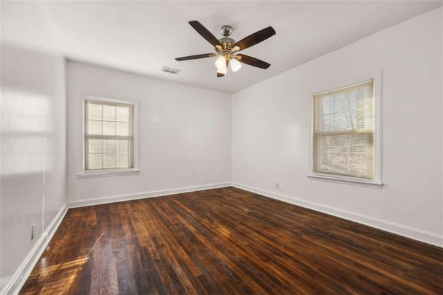 empty room with a ceiling fan, wood finished floors, visible vents, and baseboards