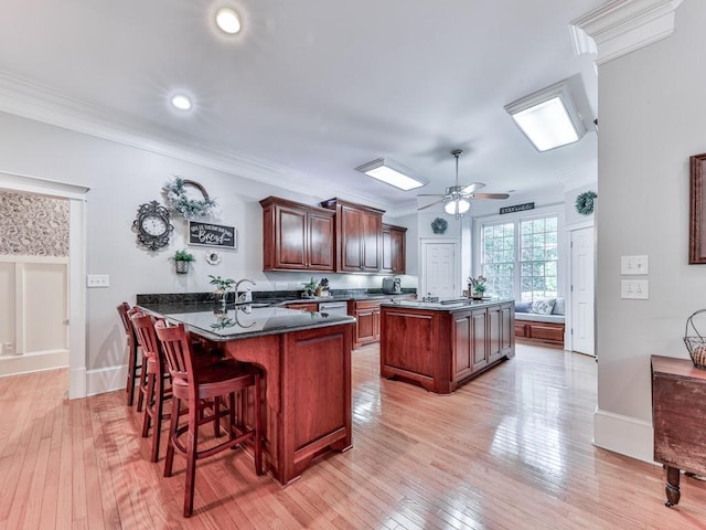275 Frances Rd, Canton, GA 30114 - kitchen featuring a center island, a breakfast bar area, light wood-style floors, ornamental molding, and a ceiling fan