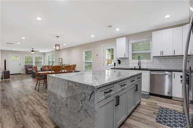 kitchen with pendant lighting, dishwasher, sink, dark stone counters, and a center island