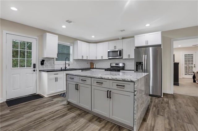 kitchen featuring white cabinetry, stainless steel appliances, a center island, and sink