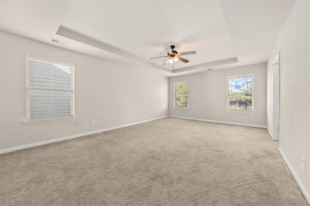 carpeted spare room featuring a raised ceiling and ceiling fan