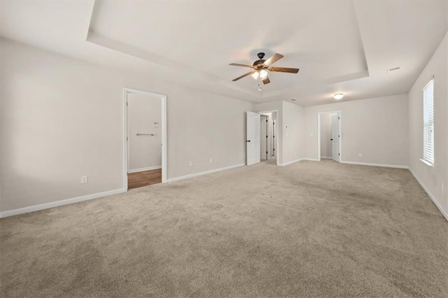 carpeted empty room with ceiling fan and a tray ceiling