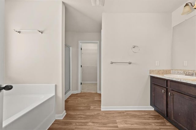 bathroom with wood-type flooring, vanity, and plus walk in shower