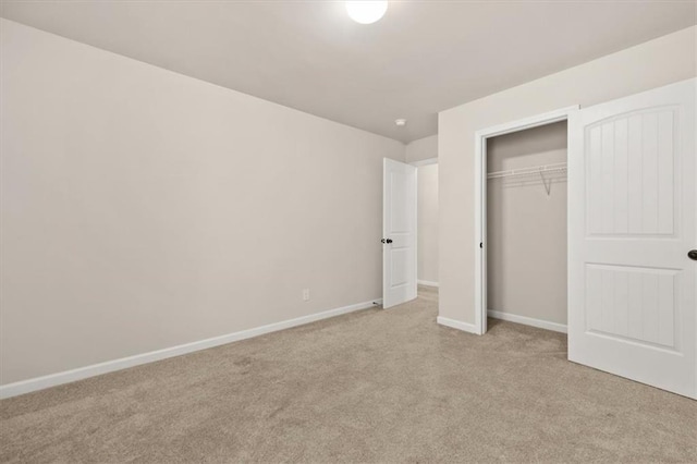 unfurnished bedroom with light colored carpet and a closet