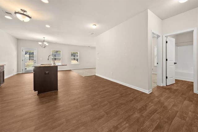 kitchen with sink, decorative light fixtures, dark hardwood / wood-style flooring, a chandelier, and a kitchen island with sink