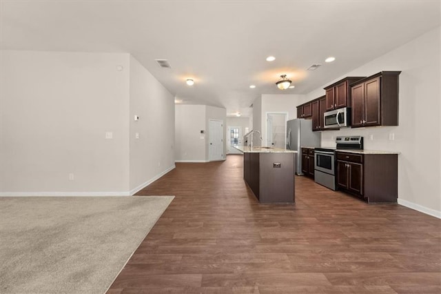 kitchen featuring stainless steel appliances, dark brown cabinets, an island with sink, and dark hardwood / wood-style floors