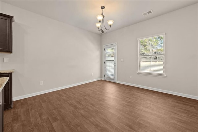 unfurnished dining area featuring an inviting chandelier and dark hardwood / wood-style floors